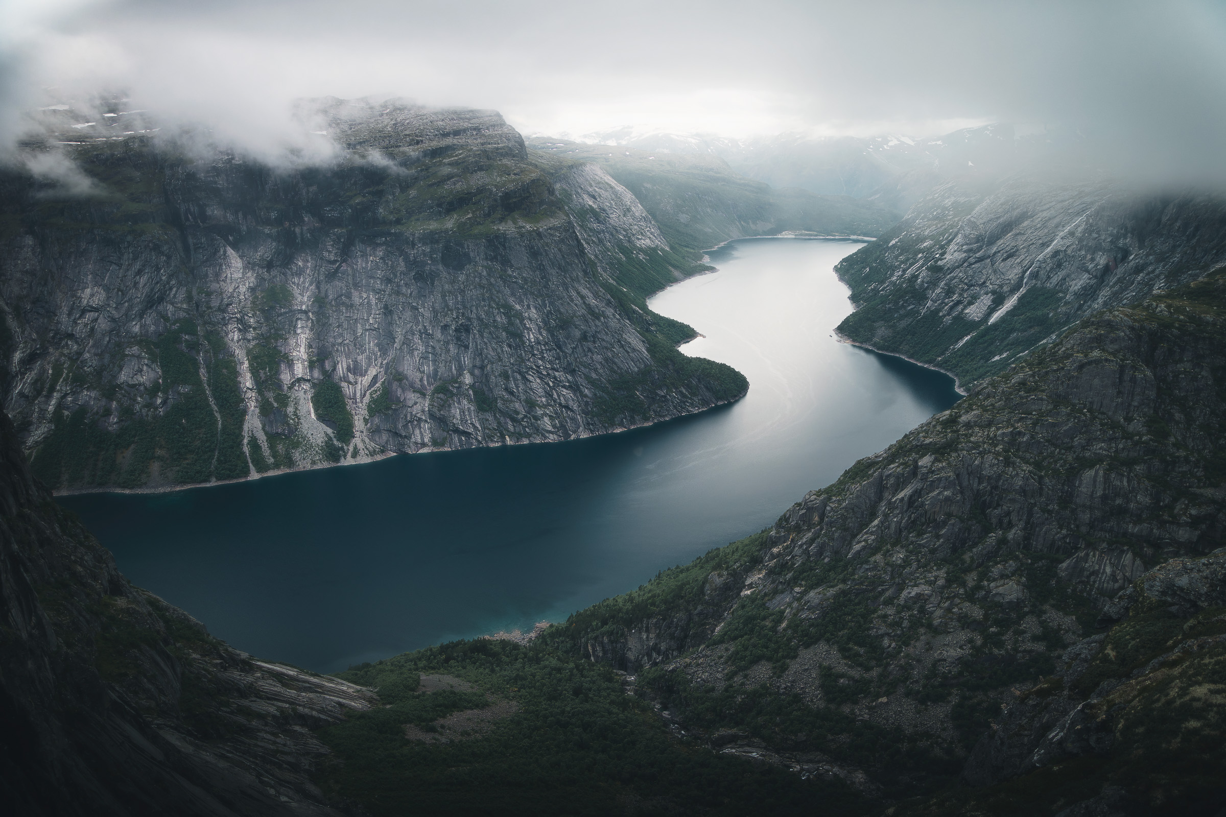 Mountain lake between steep cliffs wrapped in clouds