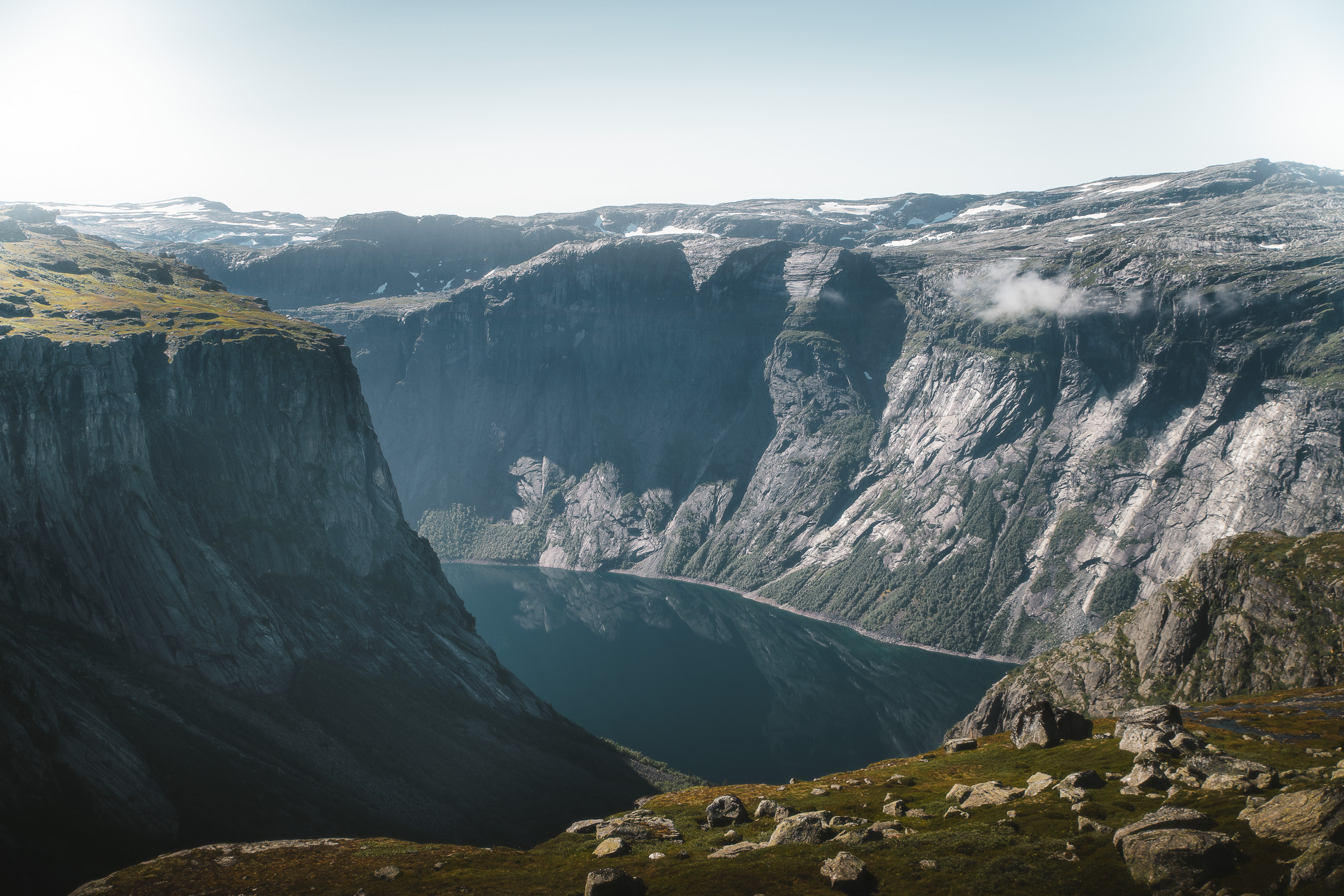 Mountain lake and vertical cliffs viewed from a rocky plateau