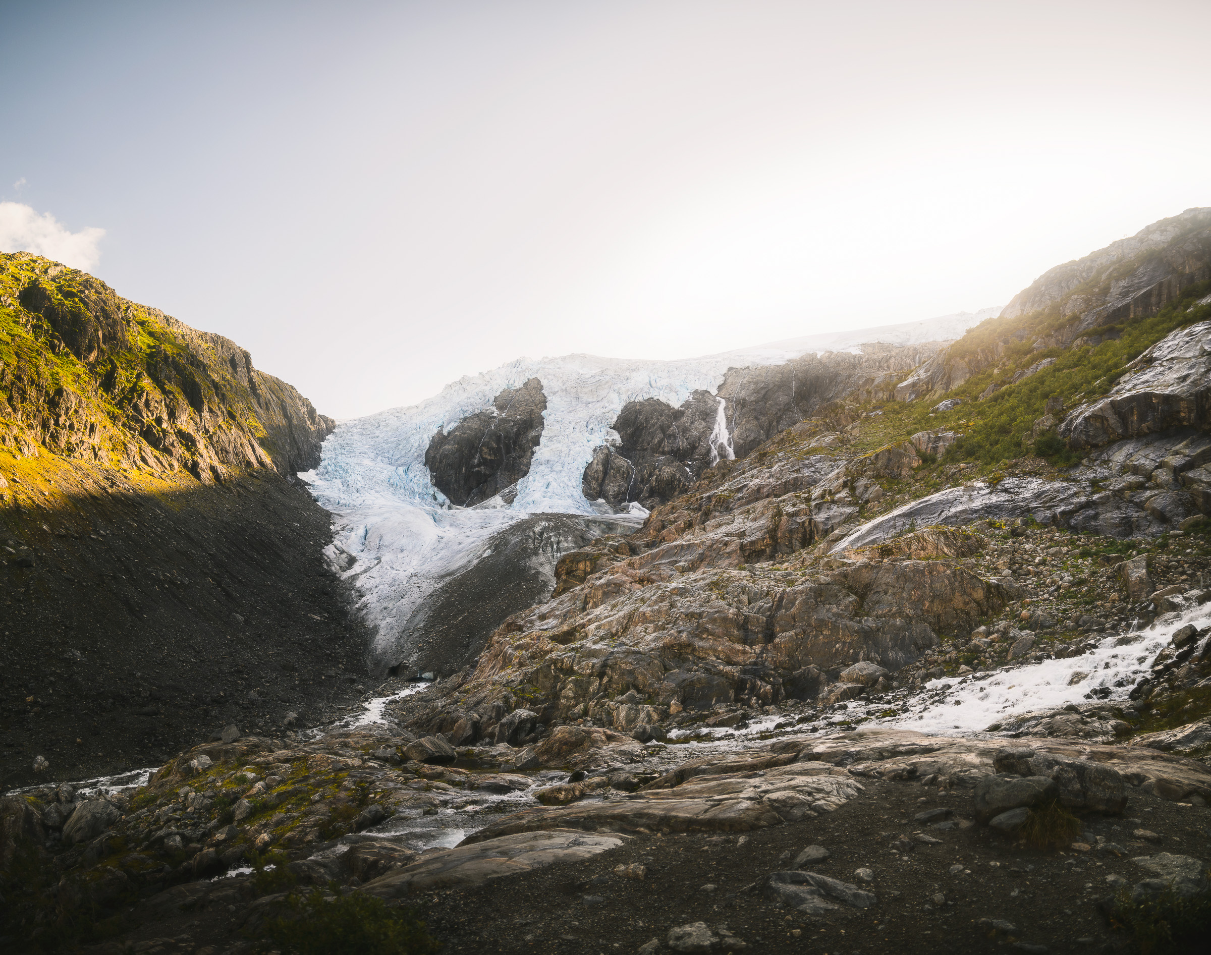 Glacier tongue descending into a rocky valley in soft sunlight