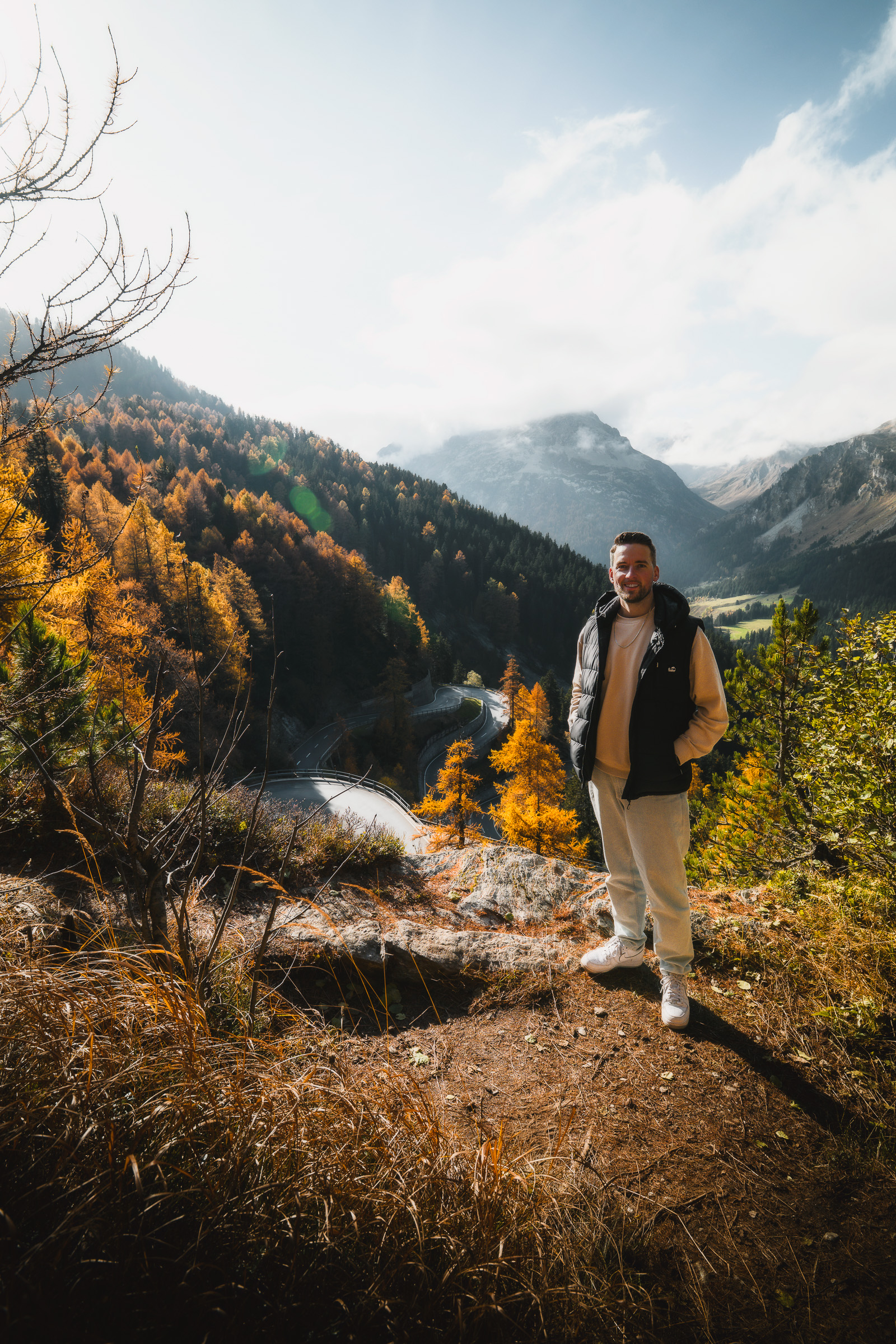 Male traveler at a viewpoint above an autumn mountain road