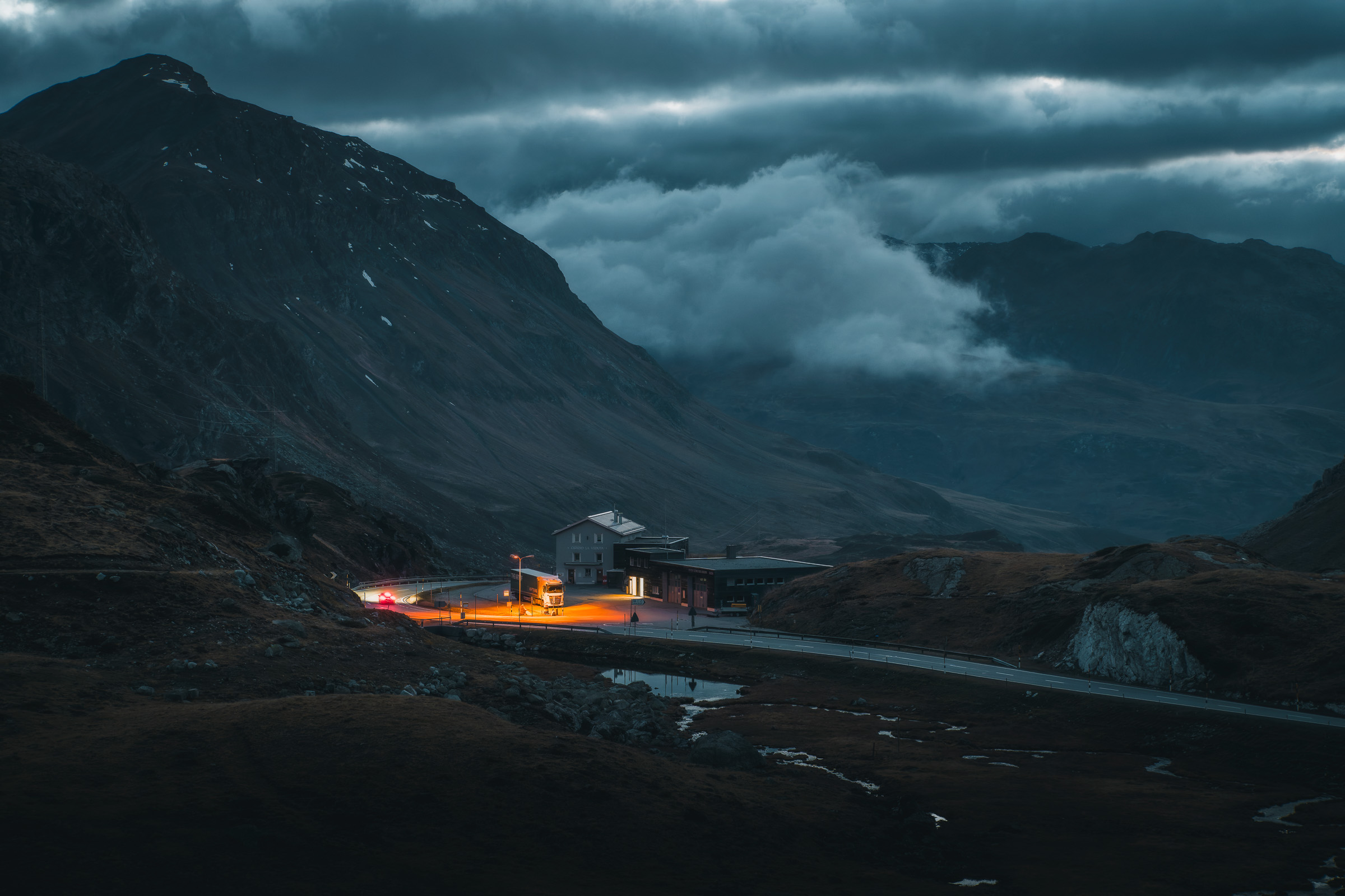 Remote mountain pass beneath dramatic storm clouds at dusk