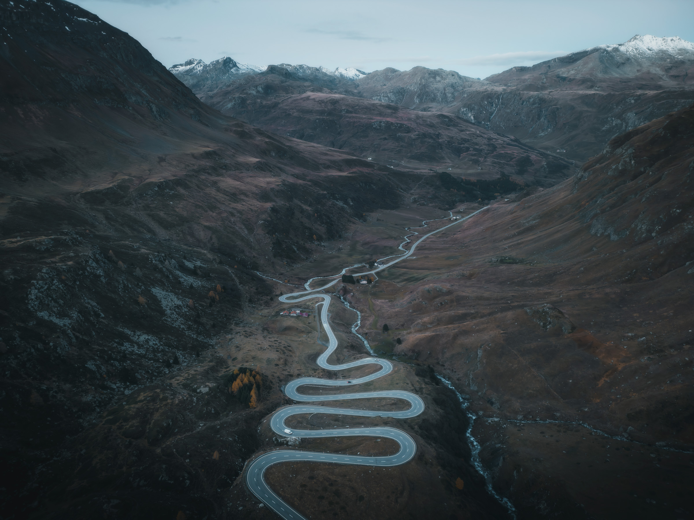 Winding pass road crossing a broad, barren alpine valley