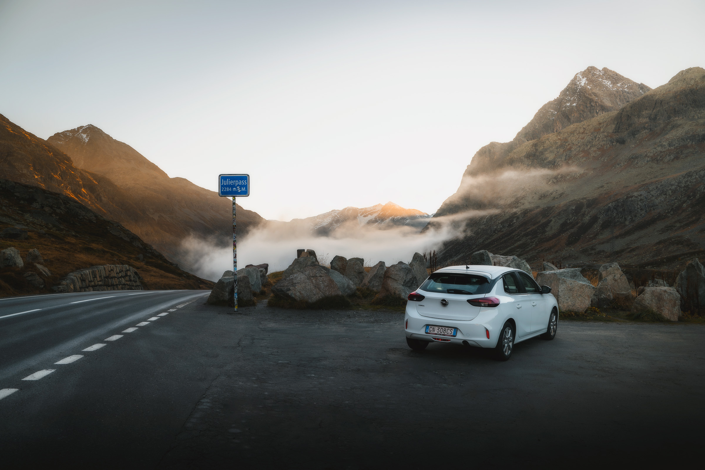 White car parked at a foggy mountain pass in Switzerland