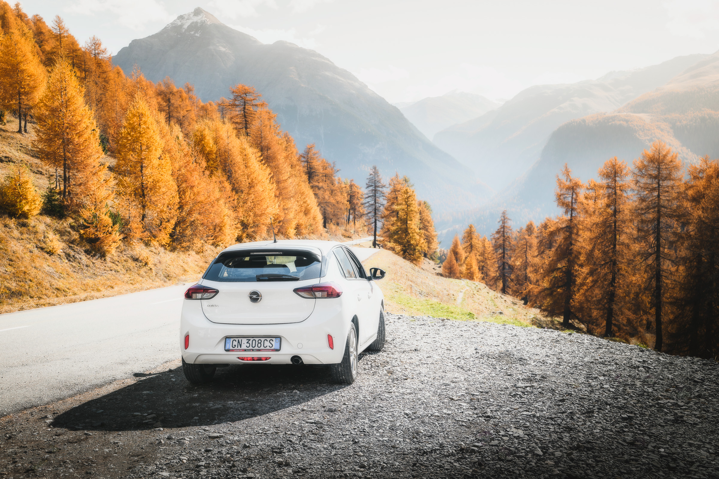 White car parked above an autumn valley in the Swiss Alps