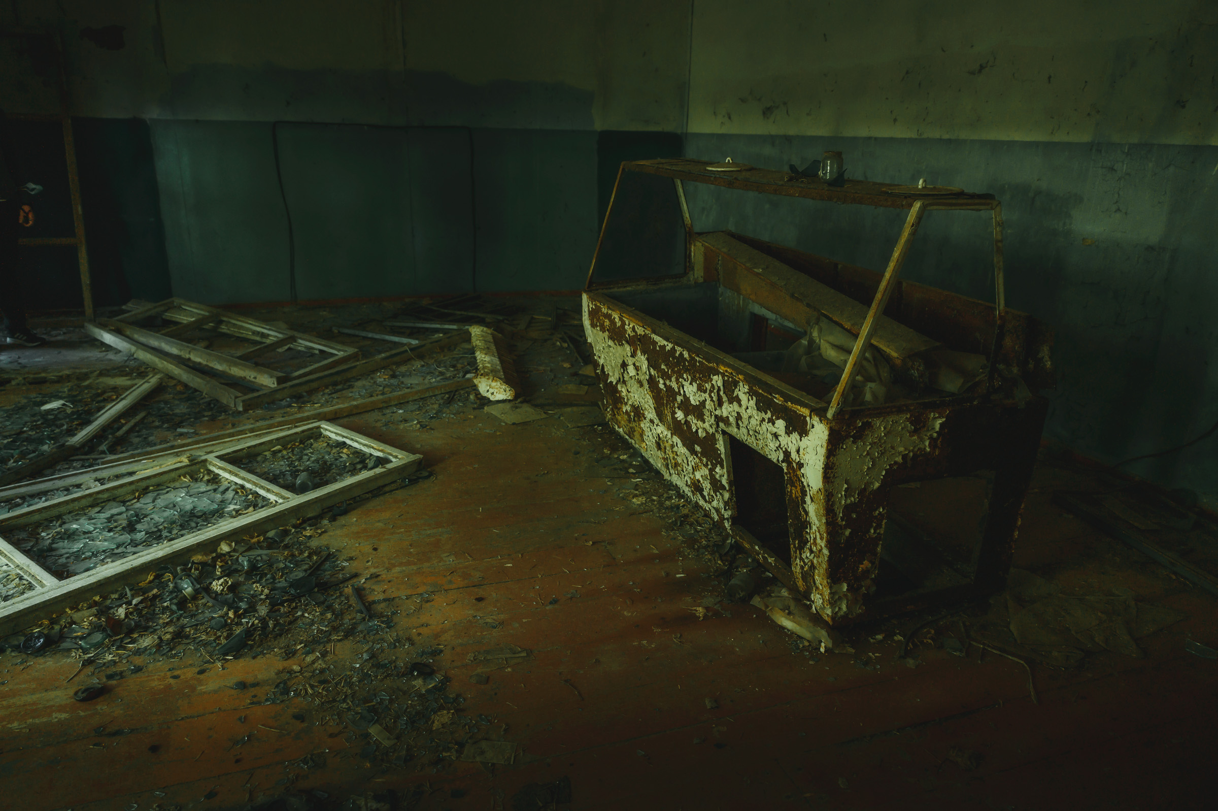 Rusted metal fixture in a debris-filled abandoned room