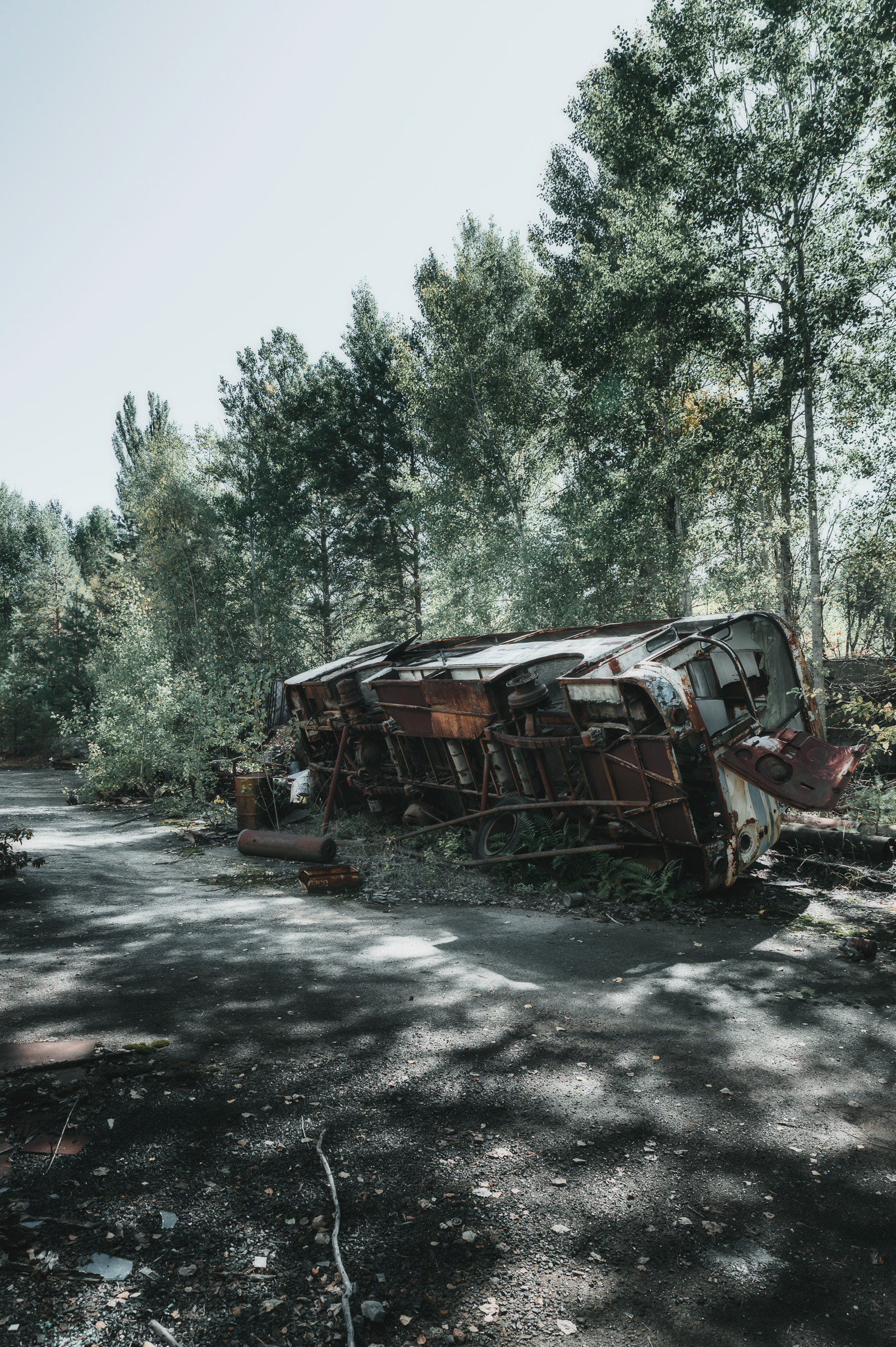 Wrecked vehicle resting on a tree-lined road in Pripyat