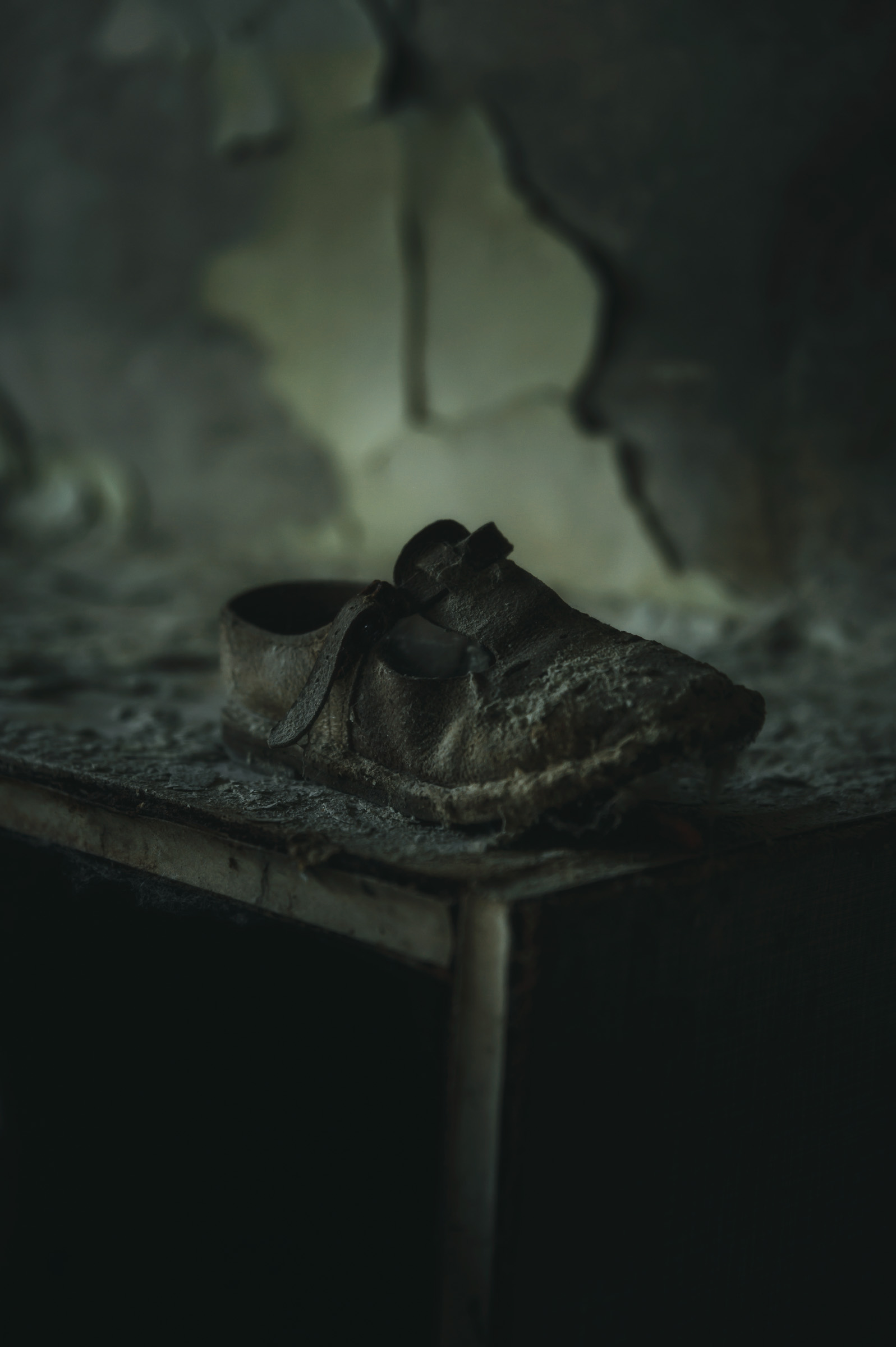 Worn shoe left on a small table in a decaying room