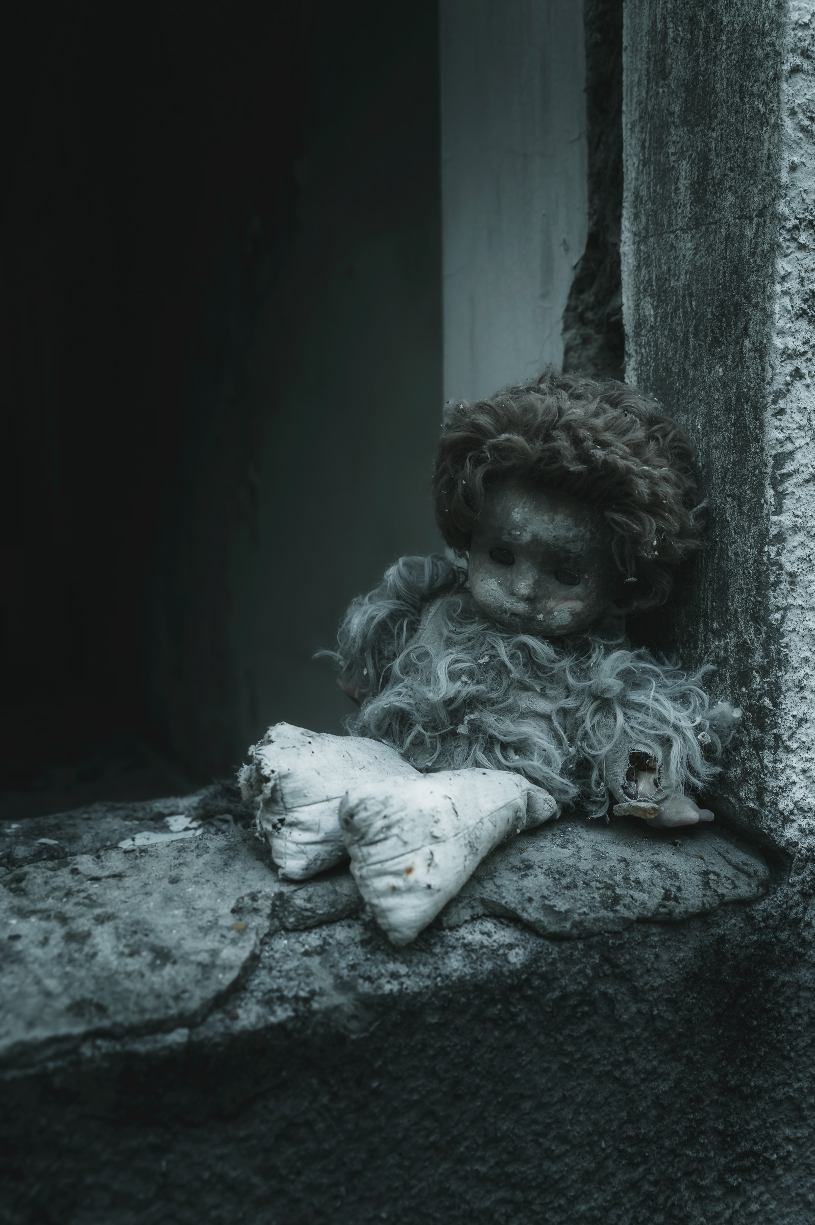 Weathered doll resting on a dusty windowsill