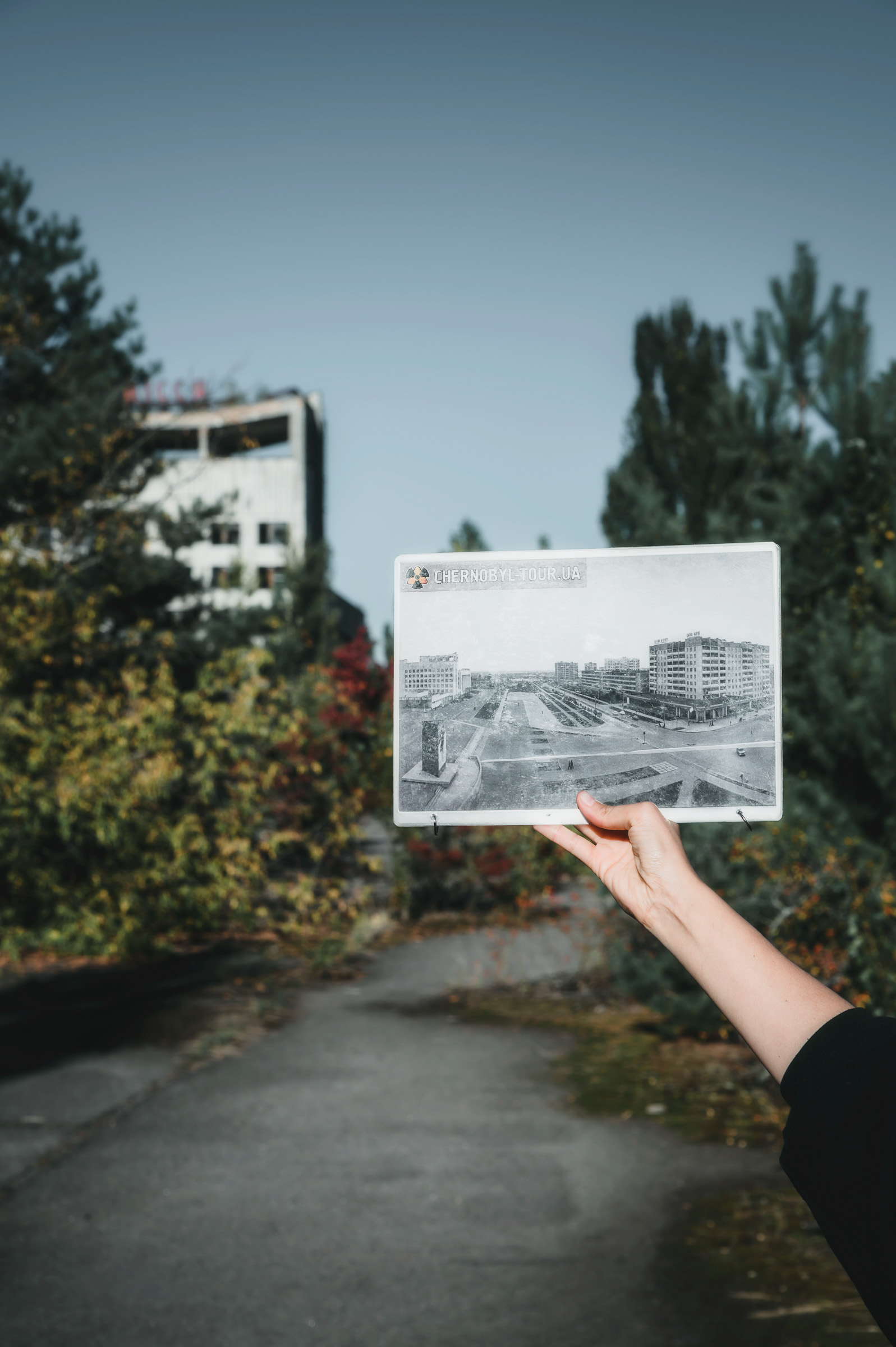 Historic photograph held before the same Pripyat streetscape