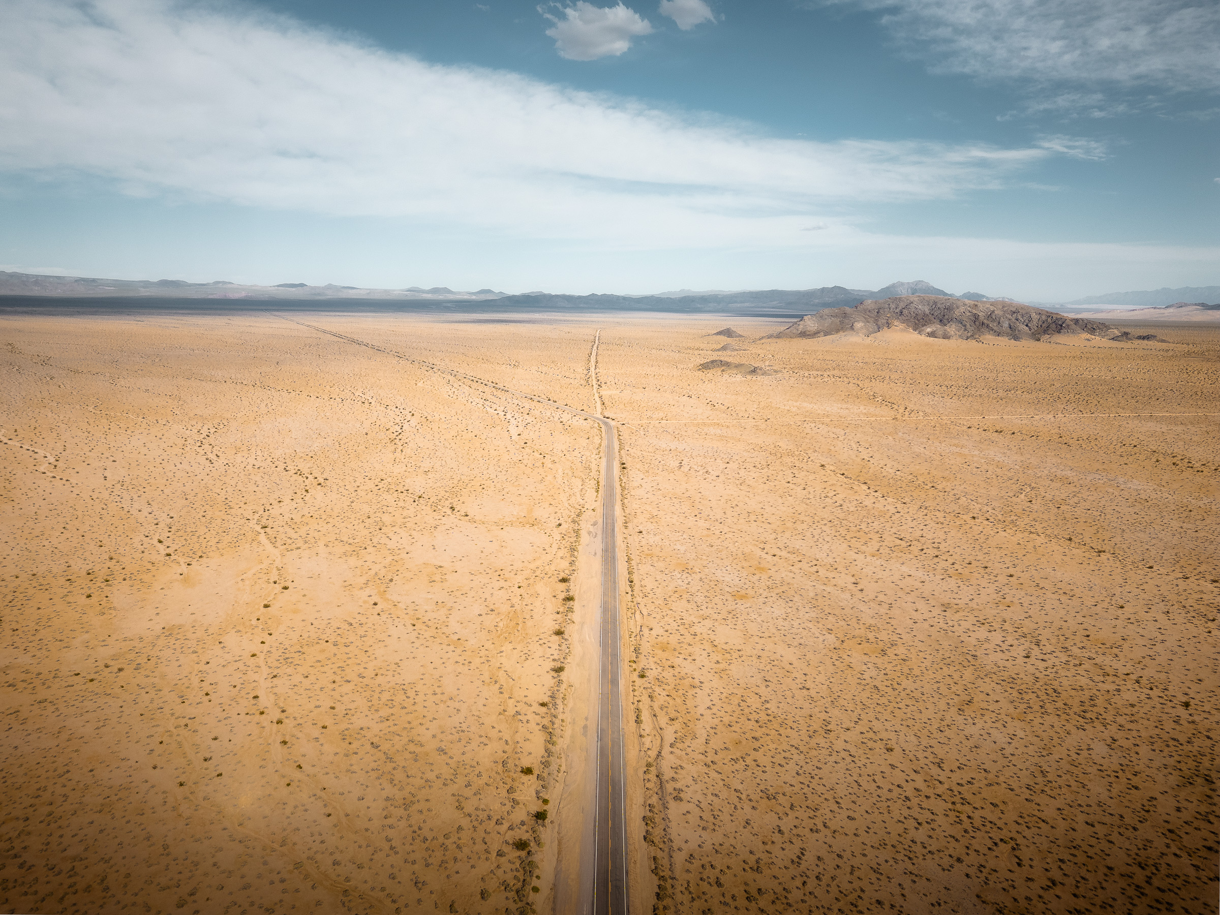 Aerial view of a straight road cutting across a vast desert