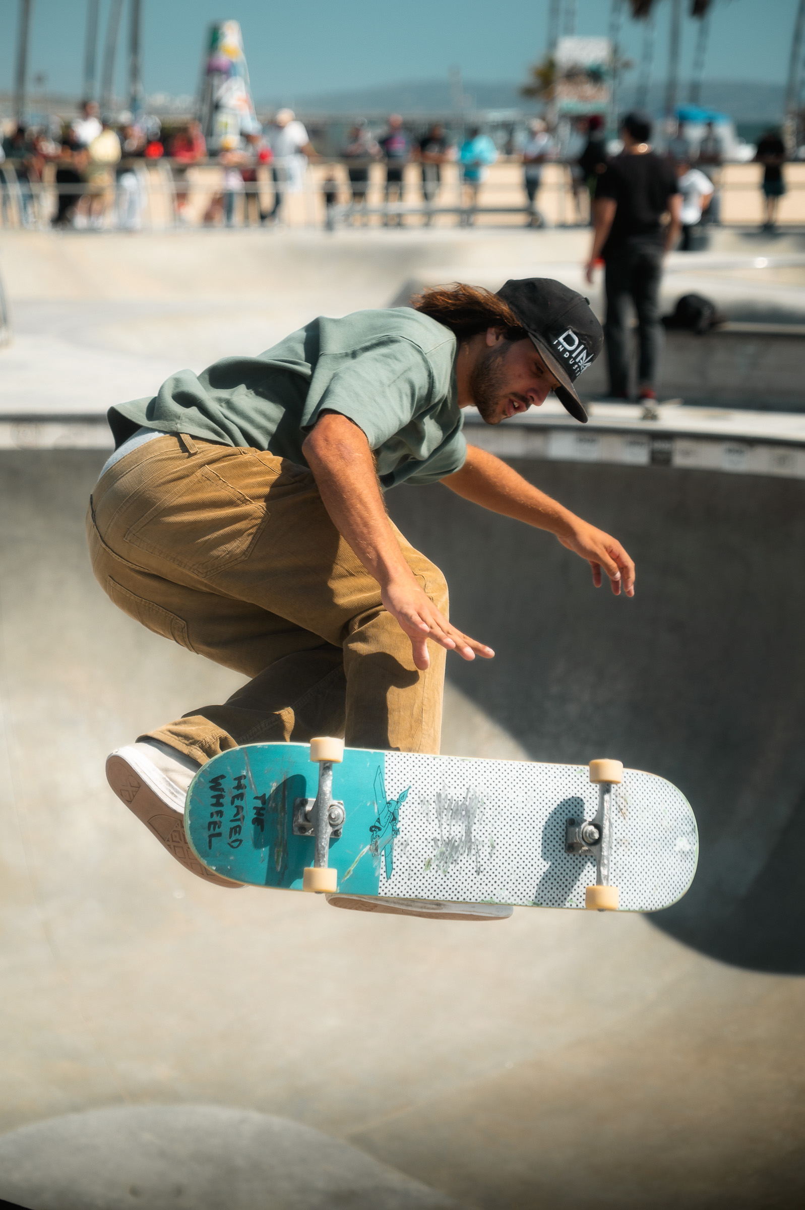 Skateboarder performing an aerial trick above a concrete bowl in Venice Beach