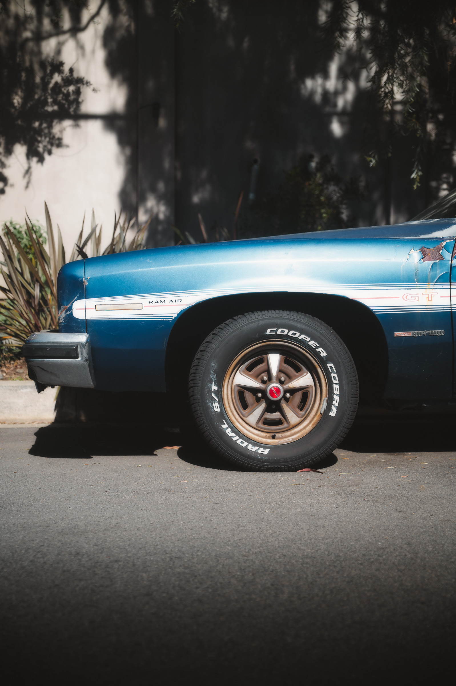 Front wheel and chrome bodywork of a vintage blue car