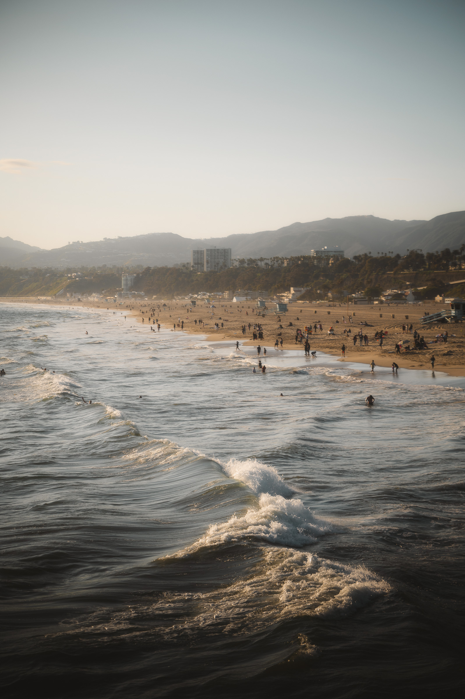 Ocean waves reaching the busy beach in Santa Monica at golden hour