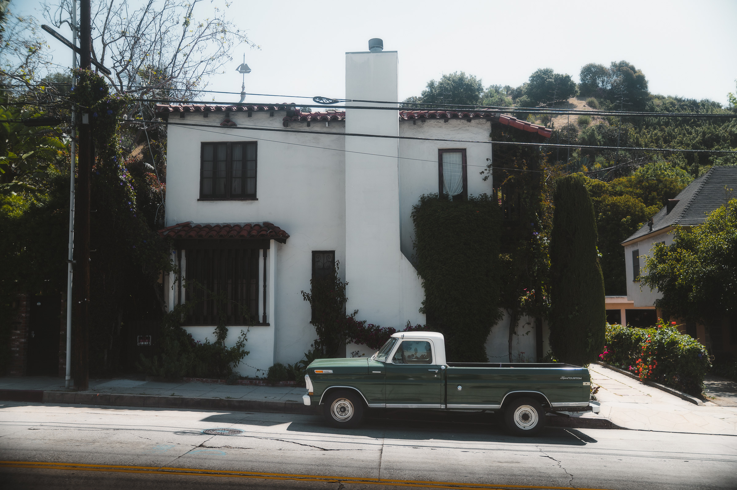 Vintage black pickup truck parked outside a white house in Los Angeles