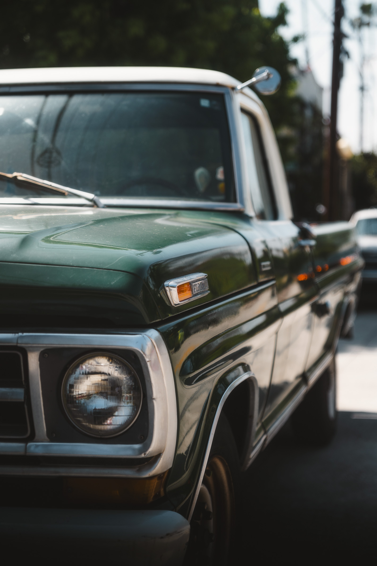 Front end of a vintage green pickup truck parked in the city