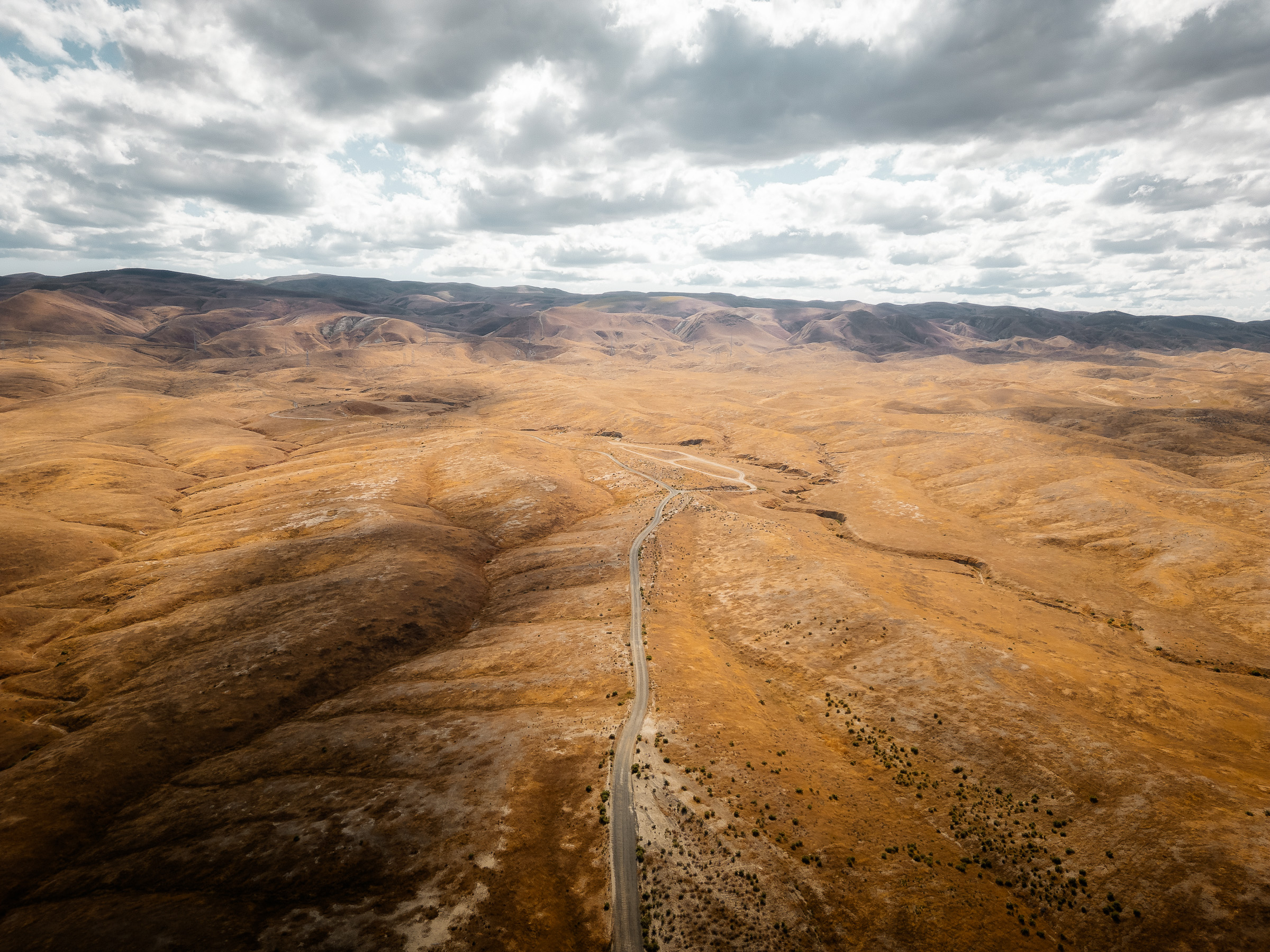 Aerial view of a straight road crossing dry rolling hills