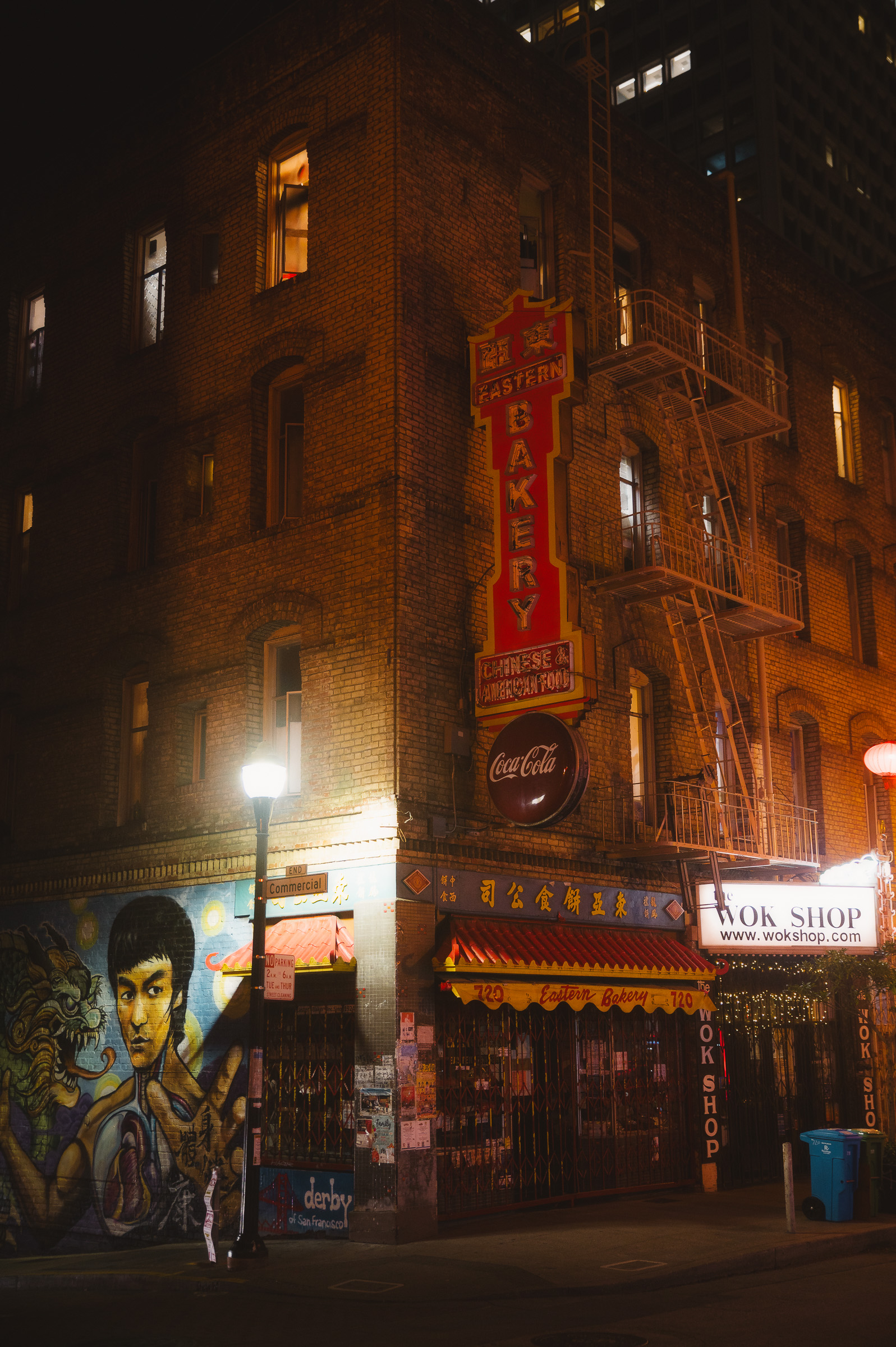 Illuminated Chinatown corner building with murals and neon signs at night