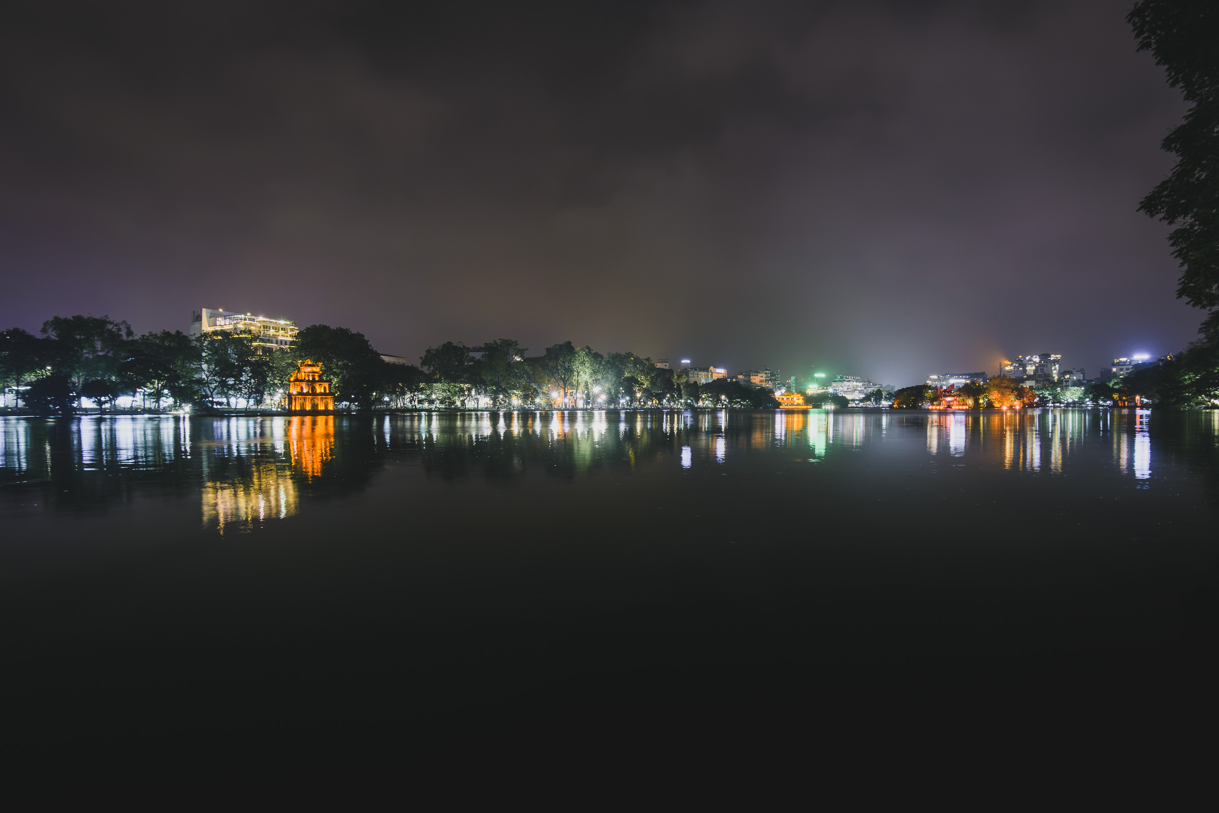 City lights reflected in a calm lake in Hanoi at night