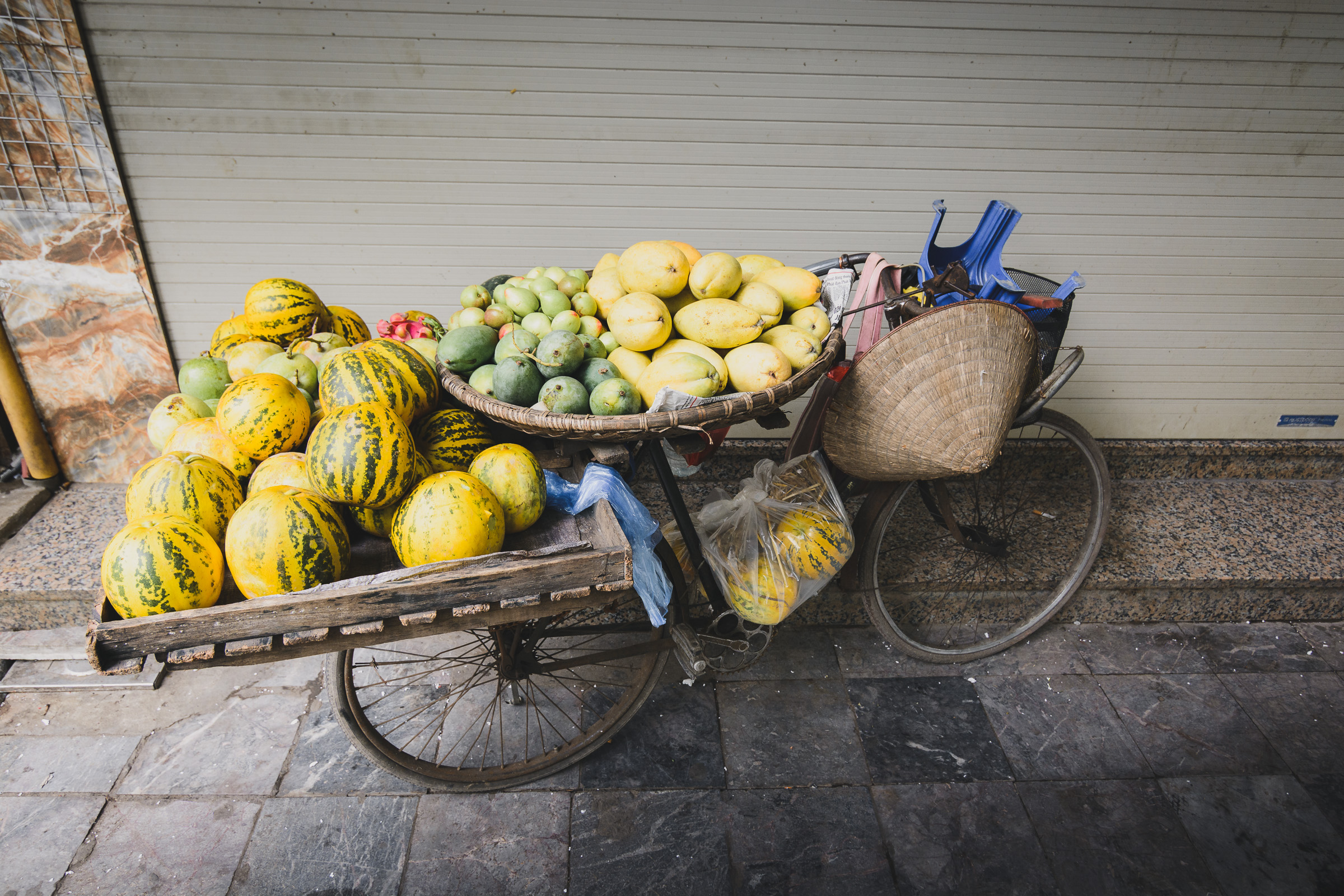 Handcart filled with melons and fresh fruit on a Hanoi sidewalk