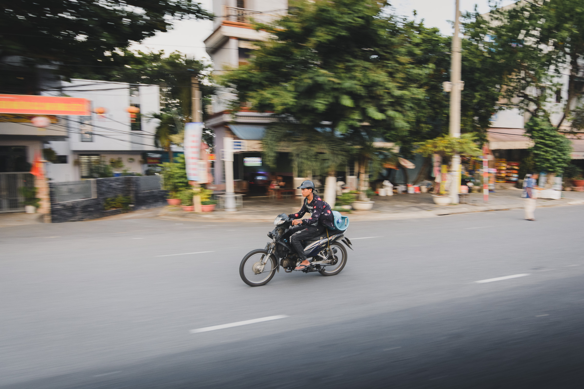 Motorcyclist riding along a busy urban street in Vietnam